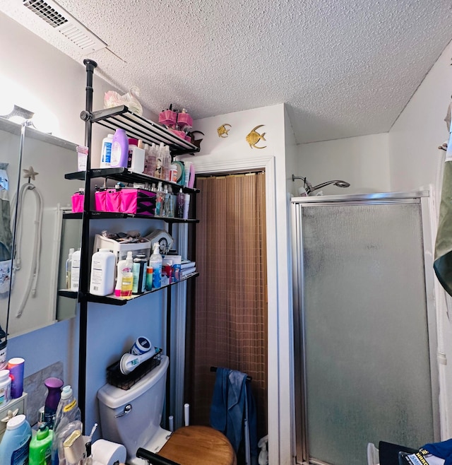 bathroom with a shower with shower door, a textured ceiling, and toilet