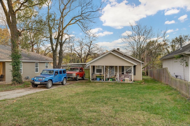 view of front of home with a front lawn, dirt driveway, fence, and a porch