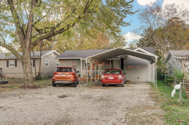 view of front of home featuring driveway, a shingled roof, and a detached carport