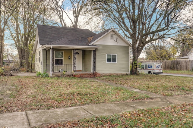 bungalow-style home with a shingled roof, fence, a porch, and a front yard