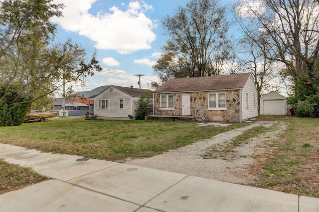 view of front of property with an outbuilding, a detached garage, driveway, stone siding, and a front lawn