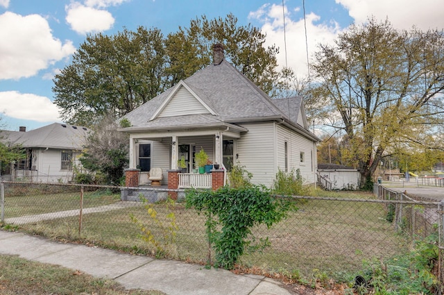 view of front of house with a porch, a fenced front yard, a shingled roof, and a front lawn