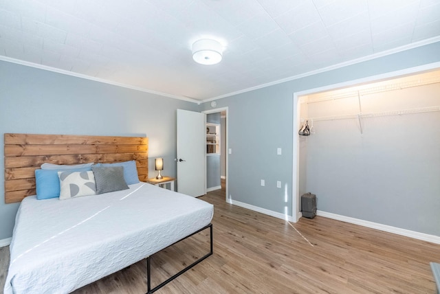 bedroom with hardwood / wood-style floors, ornamental molding, and a closet