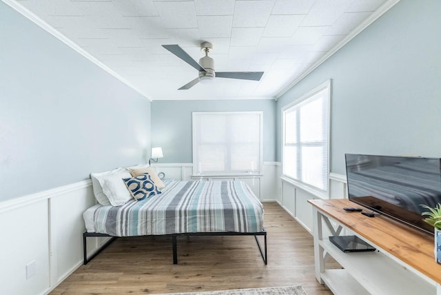 bedroom featuring ceiling fan, light wood-type flooring, and crown molding