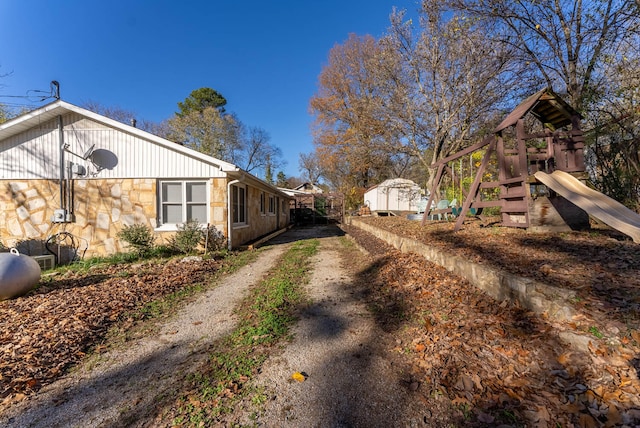 view of side of home with a storage unit and a playground