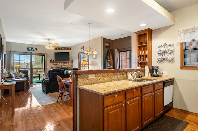 kitchen featuring sink, kitchen peninsula, white dishwasher, light hardwood / wood-style floors, and a fireplace