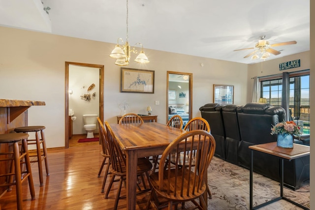 dining room with ceiling fan with notable chandelier and light hardwood / wood-style floors