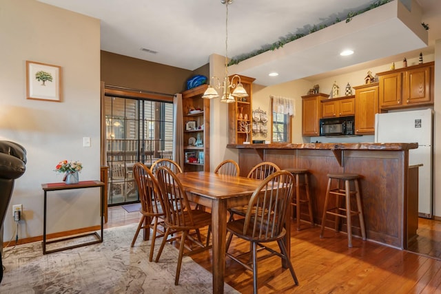 dining area with light hardwood / wood-style floors and an inviting chandelier