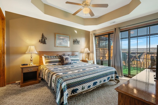 carpeted bedroom with access to exterior, ceiling fan, and a raised ceiling