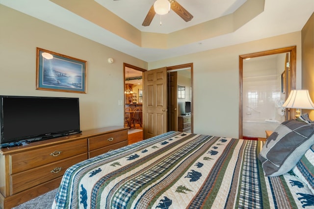 bedroom featuring connected bathroom, a raised ceiling, and ceiling fan