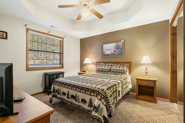 carpeted bedroom with a tray ceiling and ceiling fan