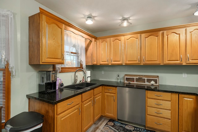 kitchen with dishwasher, light wood-type flooring, dark stone countertops, and sink