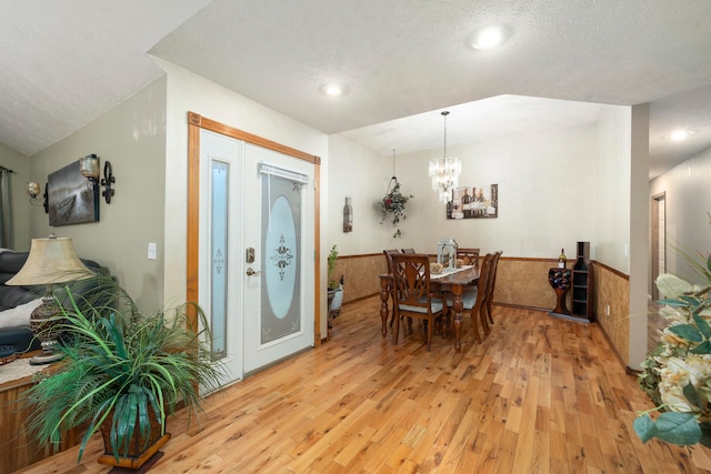 dining space featuring a textured ceiling, a notable chandelier, and light wood-type flooring