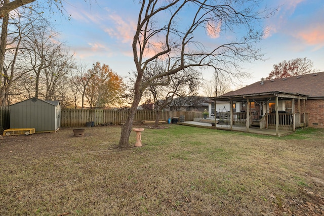 yard at dusk featuring a storage shed and a wooden deck