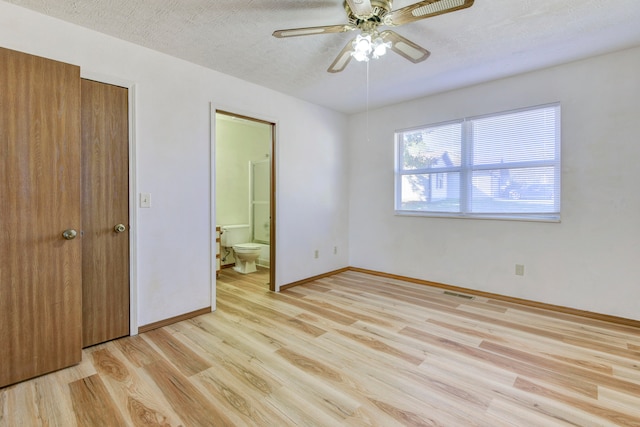 unfurnished bedroom with ceiling fan, a textured ceiling, connected bathroom, and light hardwood / wood-style flooring