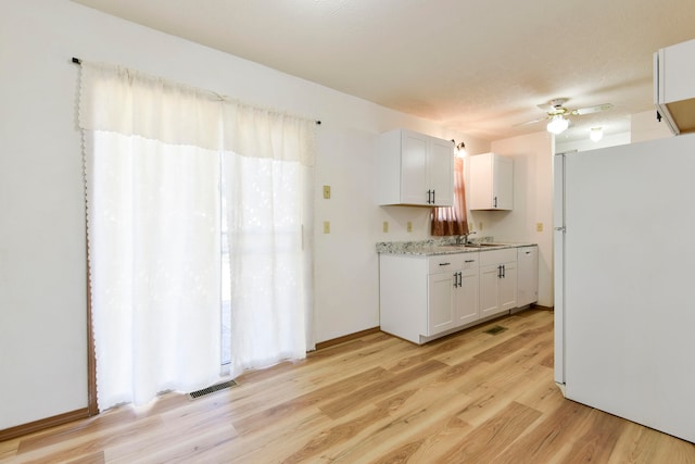 kitchen featuring white refrigerator, sink, ceiling fan, light hardwood / wood-style floors, and white cabinetry