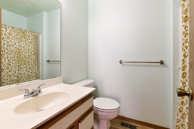 bathroom featuring a textured ceiling, vanity, hardwood / wood-style flooring, and toilet