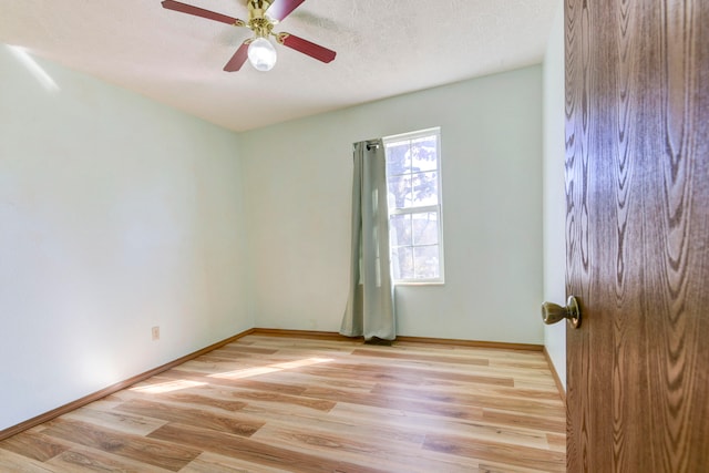 empty room featuring a textured ceiling, light wood-type flooring, and ceiling fan