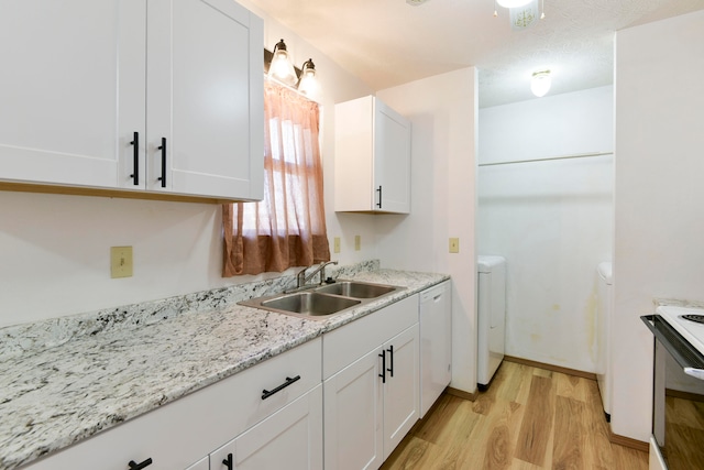 kitchen with white electric stove, sink, light hardwood / wood-style floors, washer / dryer, and white cabinetry