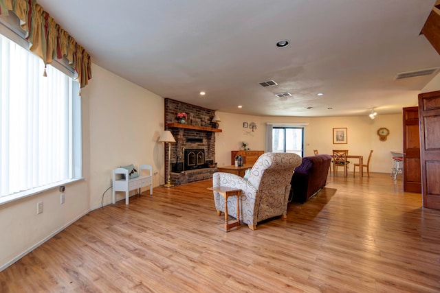 living room featuring light wood-type flooring and a brick fireplace