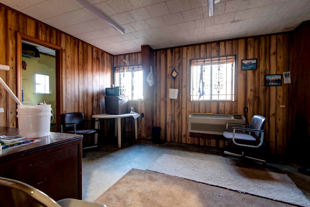 office featuring a wall unit AC, wooden walls, and concrete floors