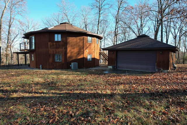 view of property exterior featuring a balcony, an outdoor structure, central AC unit, a garage, and a lawn