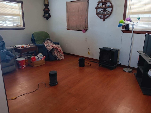 interior space featuring baseboards, wood finished floors, and a wood stove