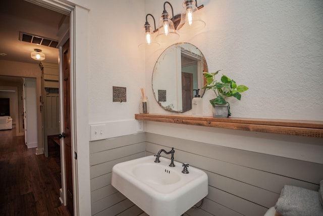 bathroom with wood walls, sink, and hardwood / wood-style floors