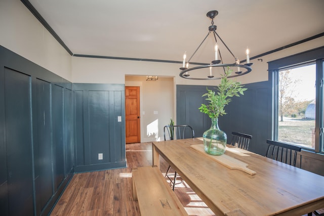 dining room with crown molding, wood-type flooring, and an inviting chandelier