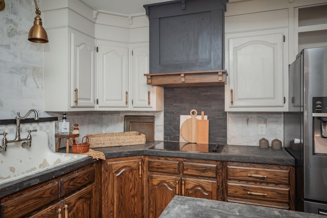 kitchen with black electric stovetop, sink, stainless steel refrigerator with ice dispenser, tasteful backsplash, and white cabinetry