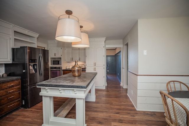 kitchen with appliances with stainless steel finishes, dark hardwood / wood-style flooring, a center island, and white cabinetry