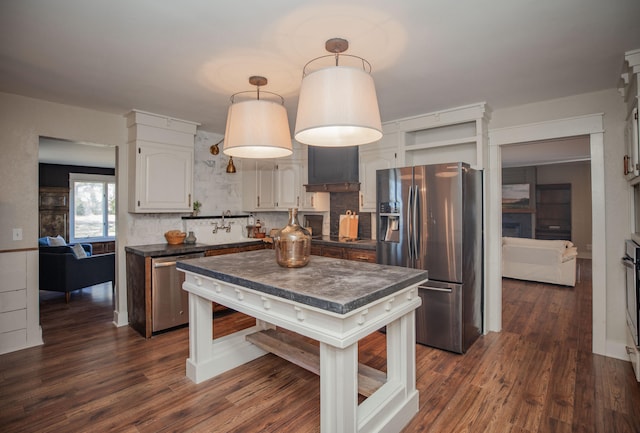 kitchen with dark hardwood / wood-style flooring, stainless steel appliances, decorative light fixtures, white cabinets, and a kitchen island