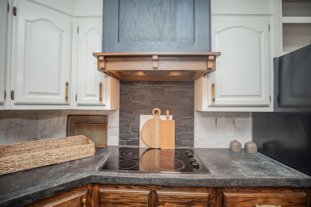 kitchen featuring white cabinets, black electric stovetop, and decorative backsplash