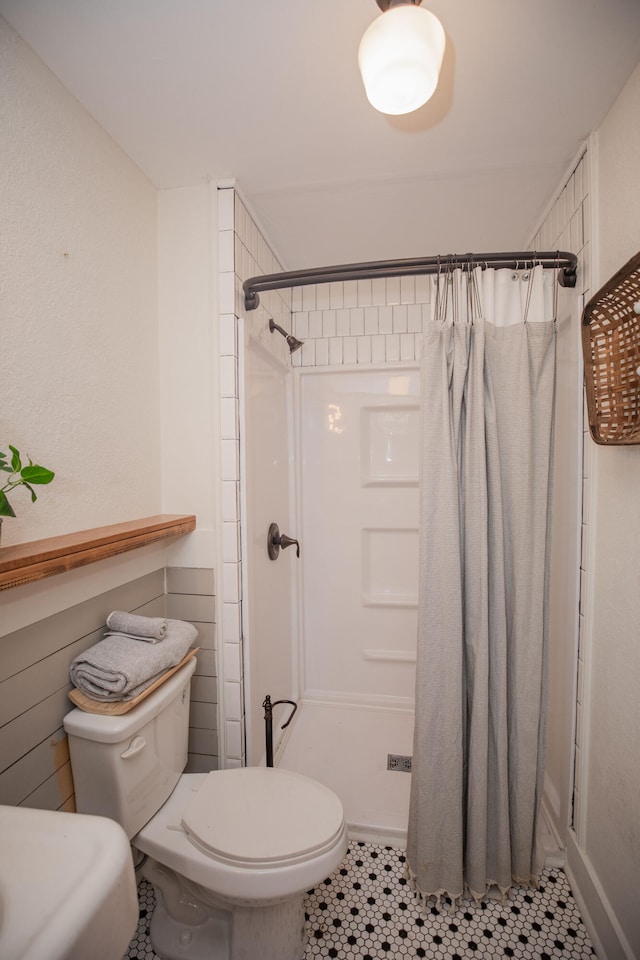 bathroom with tile patterned flooring, a shower with curtain, and toilet