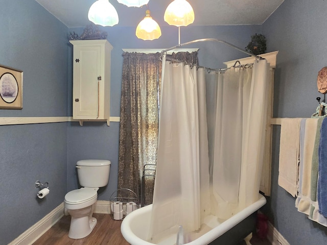 bathroom with hardwood / wood-style floors, shower / bath combo, and toilet