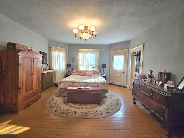 bedroom with a textured ceiling, light wood-type flooring, and a notable chandelier