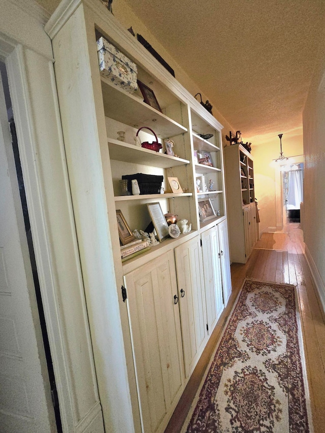 hallway with a textured ceiling and light wood-type flooring