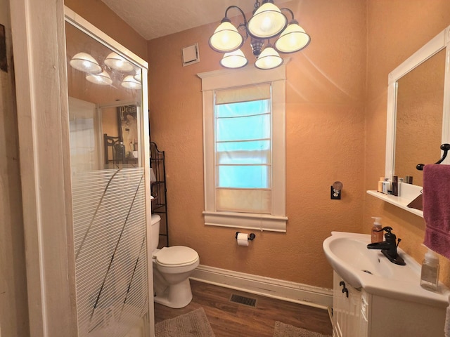 bathroom featuring vanity, a textured ceiling, an inviting chandelier, hardwood / wood-style floors, and toilet