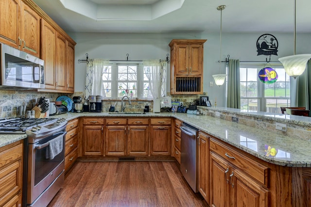 kitchen with sink, hanging light fixtures, stainless steel appliances, dark hardwood / wood-style floors, and kitchen peninsula