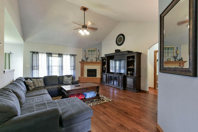 living room with dark hardwood / wood-style floors, ceiling fan, a fireplace, and vaulted ceiling