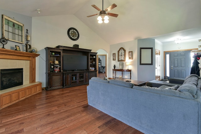 living room featuring dark hardwood / wood-style floors, ceiling fan, lofted ceiling, and a tiled fireplace