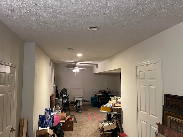 interior space featuring carpet flooring, a textured ceiling, and ceiling fan