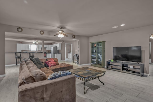 living room with ceiling fan and light hardwood / wood-style flooring