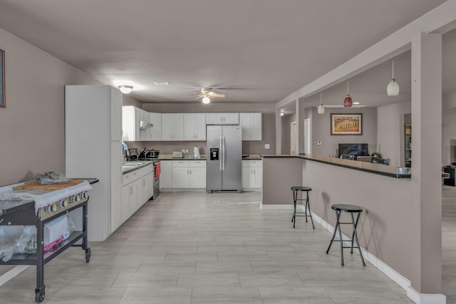 kitchen with white cabinetry, kitchen peninsula, pendant lighting, a breakfast bar area, and appliances with stainless steel finishes