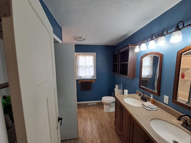 bathroom with hardwood / wood-style floors, vanity, toilet, and a textured ceiling