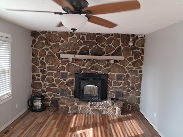 interior details featuring ceiling fan, wood-type flooring, and a wood stove