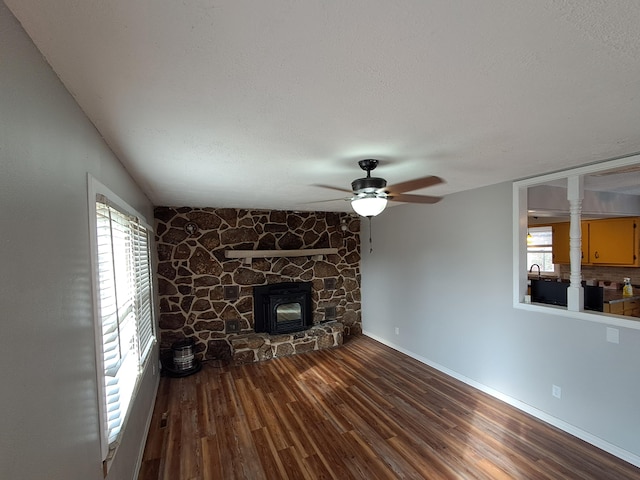 unfurnished living room with hardwood / wood-style flooring, ceiling fan, a wood stove, and a textured ceiling