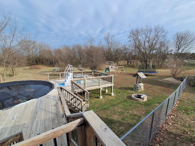 view of yard with a playground, an outdoor fire pit, a pool side deck, and a trampoline