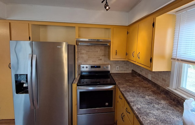 kitchen featuring decorative backsplash, appliances with stainless steel finishes, track lighting, and extractor fan