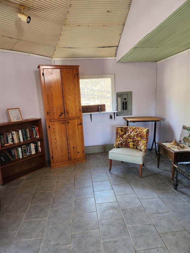 sitting room with light tile patterned floors, electric panel, and vaulted ceiling